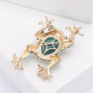 Macro detail of frog brooch back showing gold alloy texture and green stone inlay