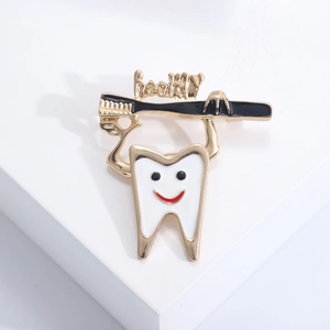 Close-up of a creative white tooth enamel pin with a golden toothbrush and healthy text