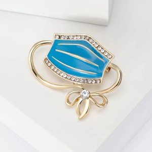 Detail of blue enamel mask brooch with gold plating and sparkling rhinestone bow accents