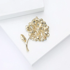 Macro view showing the sturdy safety pin clasp on the back of the golden floral brooch