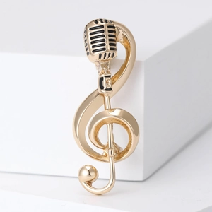 Macro detail of golden music note brooch featuring vintage microphone and treble clef design