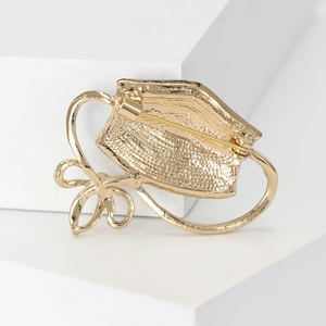 Detailed back view of a gold brooch showing hammer texture and secure safety pin clasp