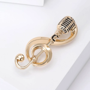 Detailed macro shot of gold musical note and microphone brooch with black enamel inlay