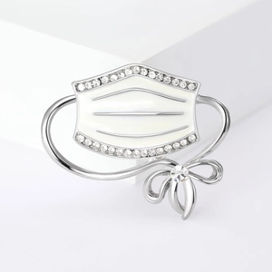 Detail of silver mask brooch with white enamel, crystal bow and sparkling rhinestones