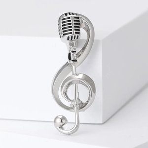 Detailed macro view of silver musical note and microphone brooch with polished finish