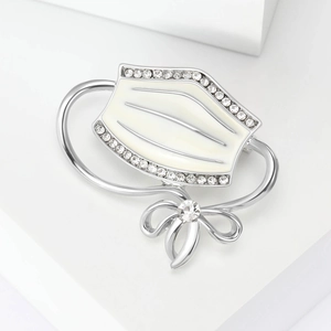 Detail of a silver enamel face mask brooch with crystal bow accent and rhinestones