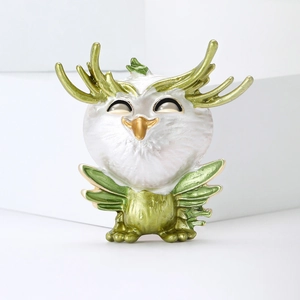 Close-up of alloy enamel owl brooch with green antlers and fine texture details