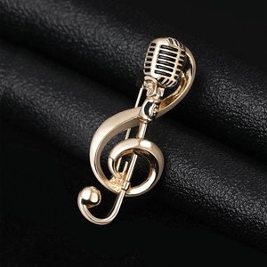Detailed macro shot of a golden music note brooch with microphone on black leather