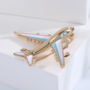 Detailed macro shot of a golden airplane brooch with blue enamel on a white stand