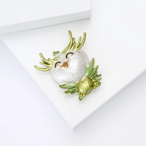 Detailed close-up of a cute enamel dragon brooch with pearl white and green finish