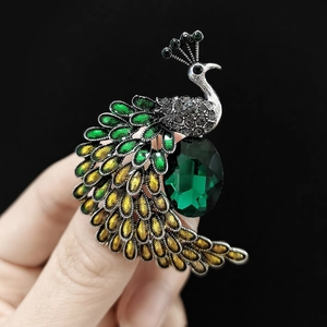 Macro d'une broche paon avec pierre précieuse vert foncé et détails en émail