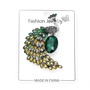 Détail d'une broche paon avec pierre verte et plumes émaillées colorées