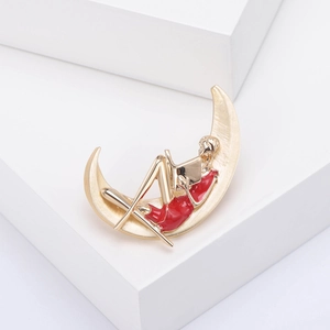 Détail de la broche lune dorée avec fille lisant, finitions artistiques en métal et émail