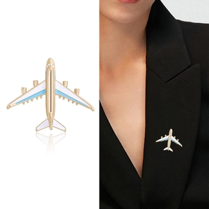 Minimalist airplane brooch in gold and blue enamel shown on white background and suit lapel
