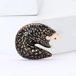 Fashionable pangolin brooch with bronze scales and black enamel on a white background