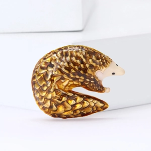 Fashionable pangolin brooch in amber resin with scale texture on minimalist white background