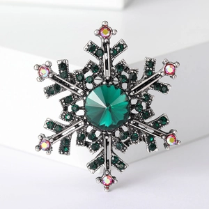 Detailed view of silver snowflake brooch with green crystal gems and rhinestones