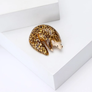 Close-up of enamel pangolin brooch with detailed brown scales and gold accents