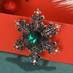 Snowflake brooch with green crystals and AB rhinestones on a festive red gift box