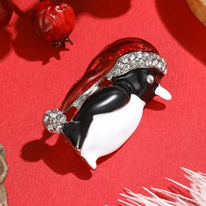 Cute cartoon penguin brooch with red Christmas hat and rhinestones on red background