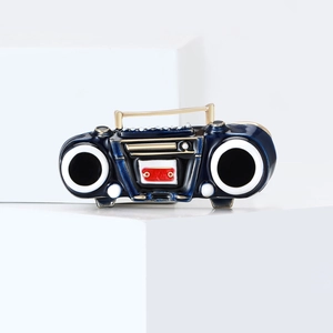 Vintage boombox brooch in blue enamel with gold accents on a white geometric background