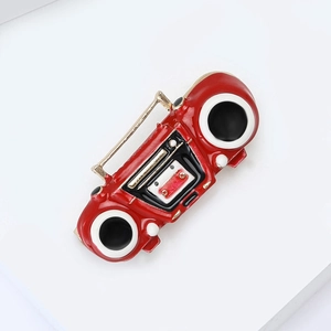 Macro detail of retro red radio alloy brooch with polished enamel finish on a white stand