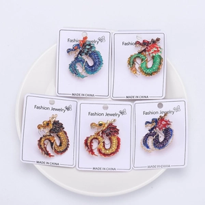 Detail of five colorful enamel dragon brooches with intricate scales on display cards