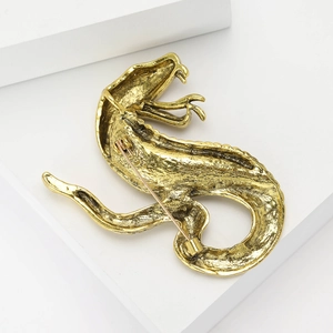 Detail view of the vintage gold cobra brooch showing the secure metal safety pin clasp