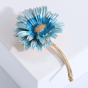 Macro detail of blue enamel daisy brooch with gold plating and gradient floral petals