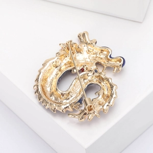 Macro shot of the golden dragon brooch back showing the long pin and secure safety cap