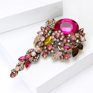 Detailaufnahme einer großen rosa Kristallbrosche mit barockem Blumenmuster aus Metall
