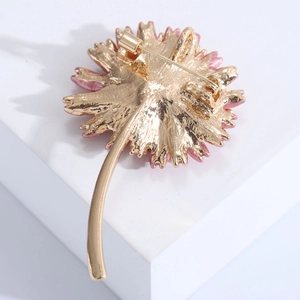 Detail view of the gold alloy base and safety pin closure on the pink daisy brooch