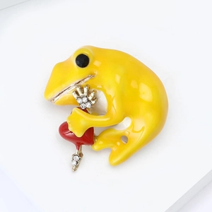 Detailed close-up of a yellow enamel frog brooch holding a red heart with rhinestones