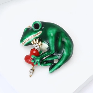 Macro detail of alloy frog brooch with green enamel, red heart, and sparkling rhinestones