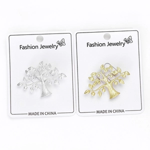 Détail des broches arbre en or et argent mat sur des cartes de bijoux de mode blanches