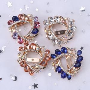 Vintage crystal glass spiral brooches in four colors on a shimmering mesh background
