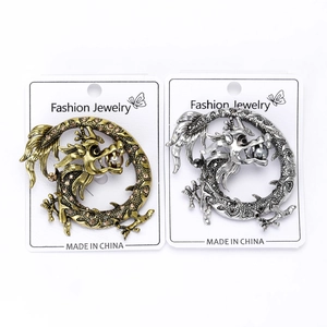 Détail des broches dragon vintage en or et argent avec des strass brillants et perles
