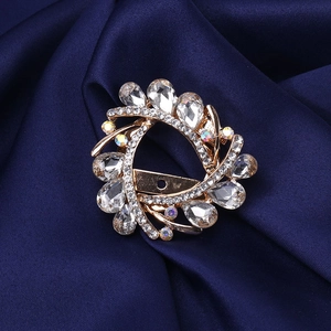 Detailed close-up of golden geometric brooch with sparkling crystal teardrops and rhinestones