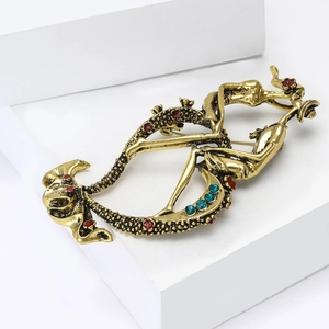 Detail of vintage gold alloy brooch with abstract art lines and colorful rhinestones