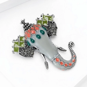 Detailed close-up of elephant brooch with grey enamel, red patterns and crystal inlay