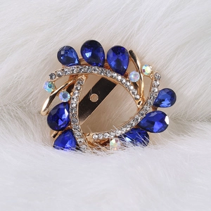 Macro shot of gold alloy brooch with blue teardrop crystals and small white diamonds on fur
