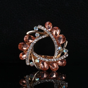 Macro shot of amber crystal wreath brooch with gold base and rhinestones on black background