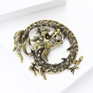 Gros plan détaillé de la broche dragon rétro avec strass champagne et perle centrale
