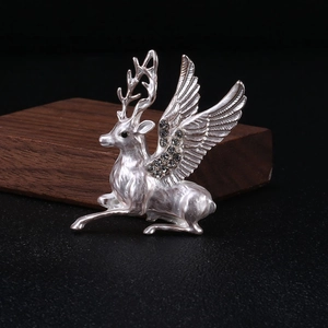 Macro shot of silver flying deer brooch with sparkling crystals on dark wood base