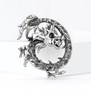 Broche dragon vintage avec strass noirs et perle sur un fond géométrique blanc