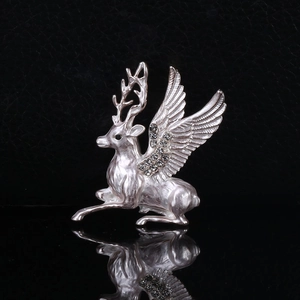 Detailed macro view of a silver reindeer brooch with rhinestone wings on a dark surface