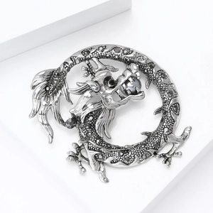 Gros plan sur une broche dragon avec des strass foncés et une perle grise élégante