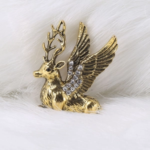 Macro detail of vintage gold winged reindeer brooch with crystals on white fur background