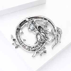 Détail de la broche dragon vintage montrant l'alliage argenté et l'incrustation de perle