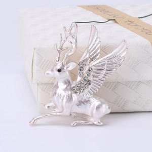 Detail shot of pearlescent white flying deer brooch with sparkling crystals in a gift box